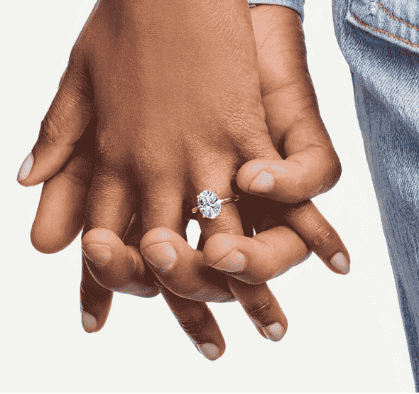 Two holding hands with an engagement ring on one of them.