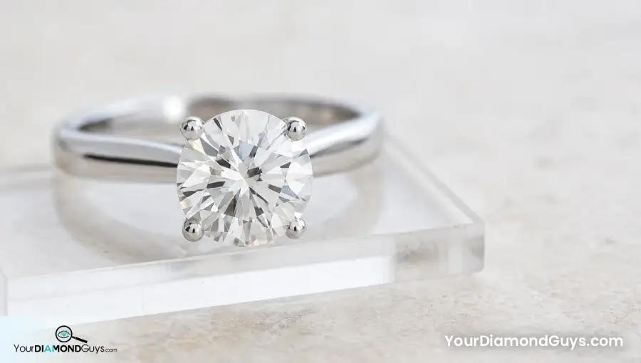 Round solitaire engagement ring on a clear acrylic pad with a clean center focus