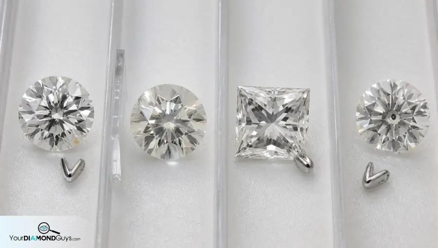 Four loose diamonds in inspection lanes showing edge crystal feather corner chip and table mark prong screen