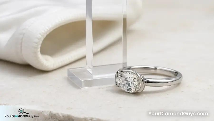 Low profile oval diamond ring checked beside a blank height gauge and glove cuff