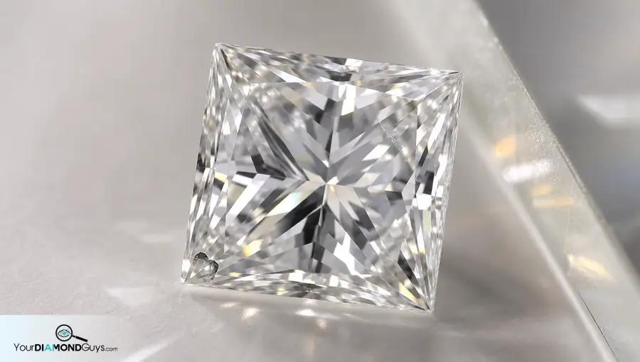 Princess cut diamond on an inspection tile showing a small corner chip and surface cavity during first-look clarity review