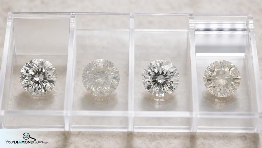 Four round diamonds in acrylic inspection lanes showing cloud and haze transparency checks