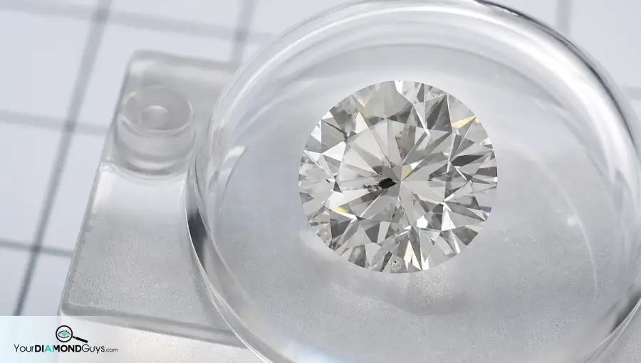 Round diamond under a clear magnifier showing a dark inclusion near the table